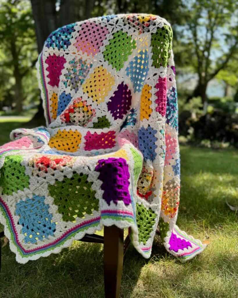 The granny square blanket on a chair outside