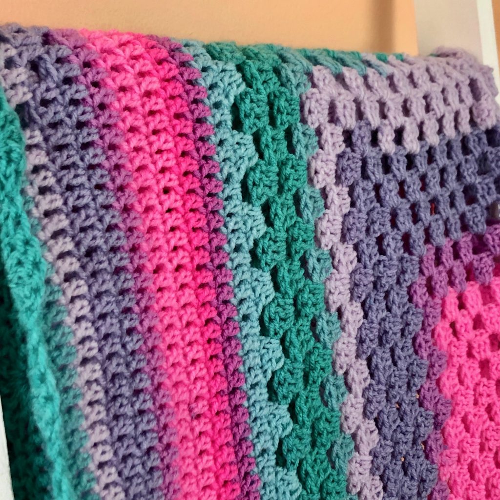 Diamond Corner Granny Baby Blanket | Crochet Pattern by MadameStitch The center #grannysquare section is followed by a solid section with a pattern of spaces that look like a diamond. #babyblanket #crochetpattern