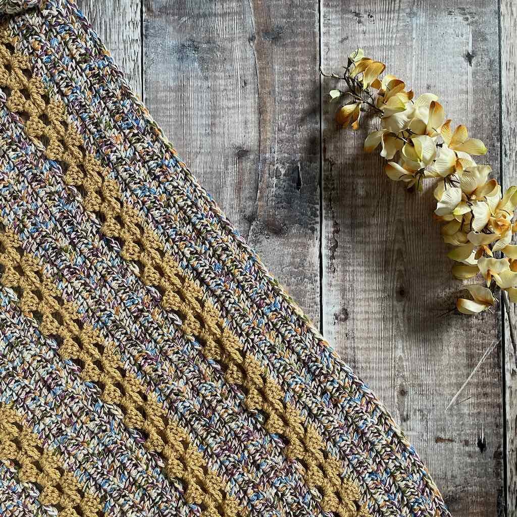 Flatlay of the granny stitch Shawl with flowers