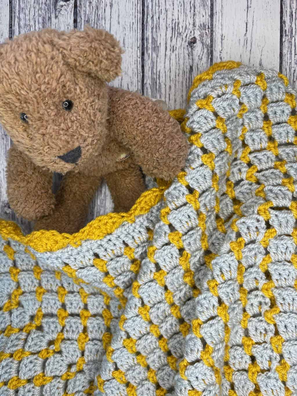 The Blissful Blocks Baby Blanket | block stitch baby blanket with teddy bear on a light wood background