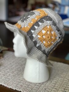 A photo of a granny square bucket hat on a styrofoam head - A crochet design by MadameStitch