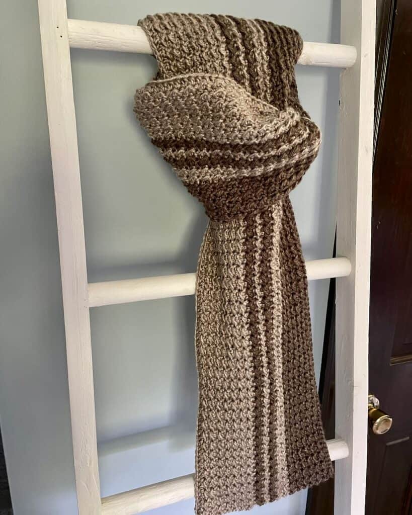 Photo of the Woodland crochet men's scarf hanging on a ladder | A crochet design by MadameStitch