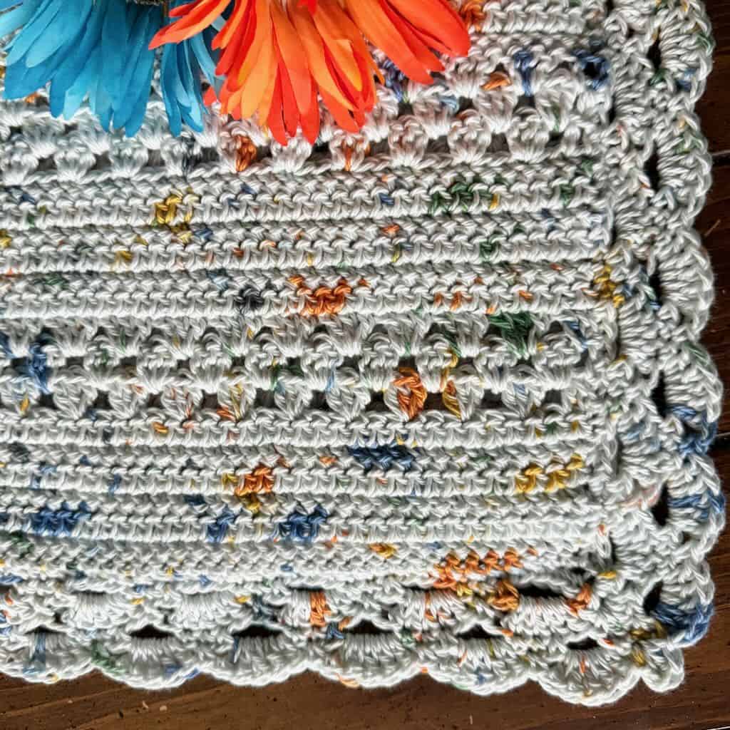 A closeup photo of a crochet baby blanket with flowers