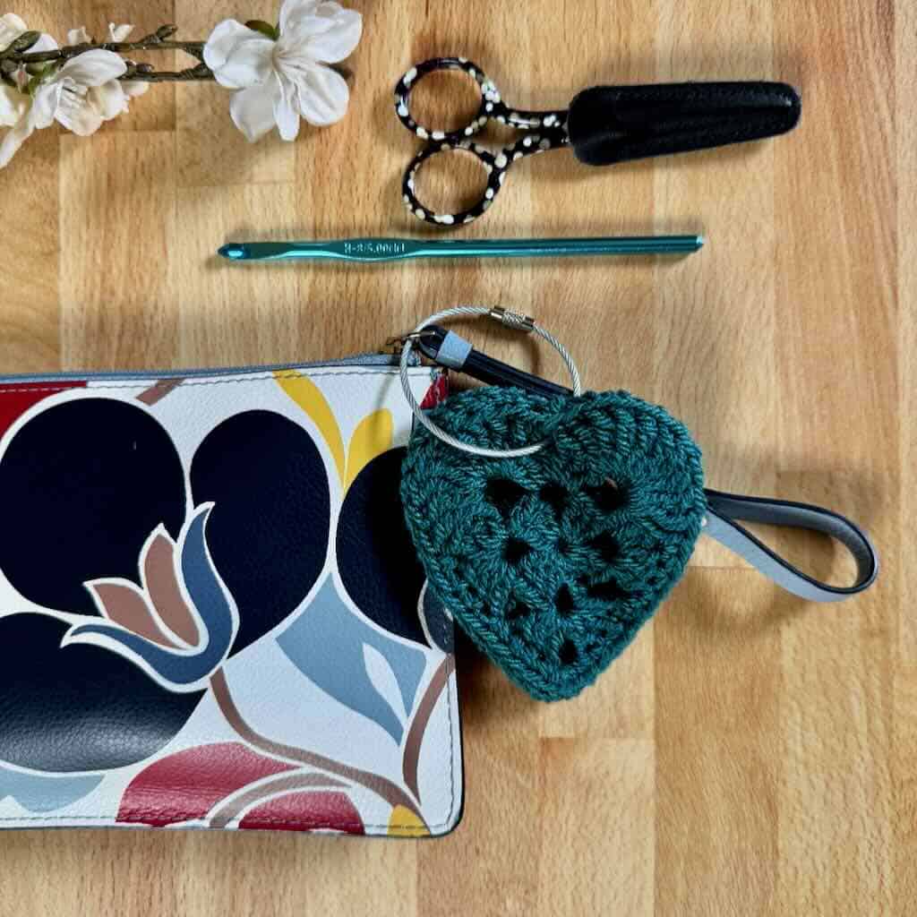 Photo of crochet heart keychain with scissors and crochet hook, pretty bag and flowers