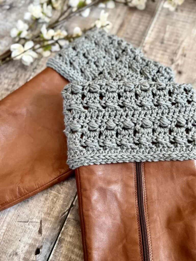 A closeup photo of crochet boot cuffs on brown boots with flowers