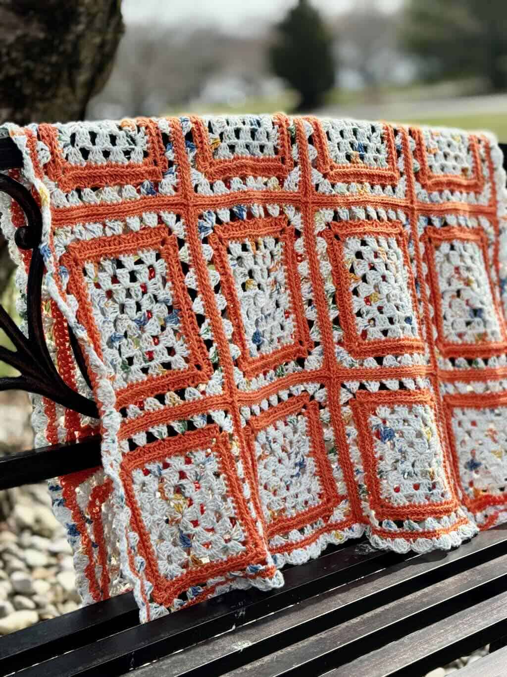 A photo of the Cream Pop granny square blanket on a bench