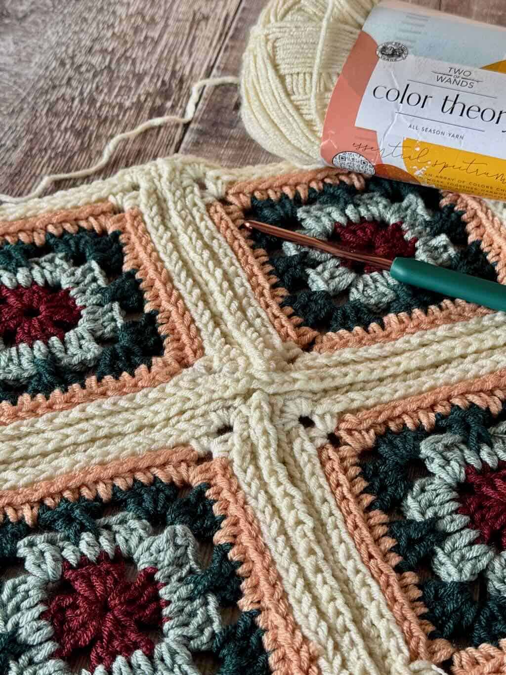 The unassembled granny square book sleeve with hook and yarn